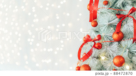 Christmas tree decorated with red bows and baubles against shiny background 88472870
