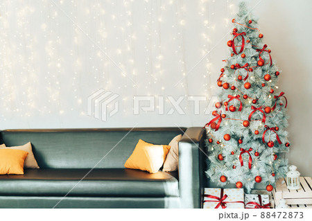 White decorated christmas tree with gift boxes standing next to the sofa 88472873