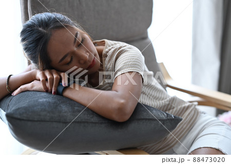 Millennial woman in casual clothes sleeping on comfortable armchair at home. Millennial woman in casual clothes sleeping on comfortable armchair at home. 88473020