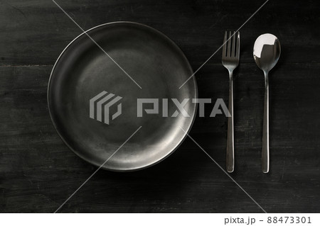 Overhead, Empty black ceramic plate with silverware on black wood table. 88473301