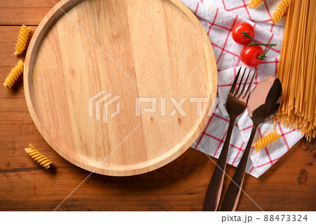 Overhead shot of an empty wood round plate, silverware on table. 88473324