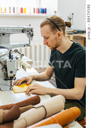Close up craftsman hands sew stuff blank for wallet use sewing machine. Working at leather workshop 88474586