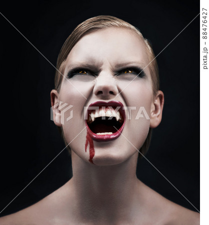 Filled with bloodlust. A provocative female vampire with blood running down her chin. 88476427