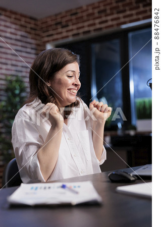 Excited enthusiastic businesswoman in workspace being motivated by salary raise. Happy positive office worker sitting at desk while celebrating successful accounting data report analysis. 88476842