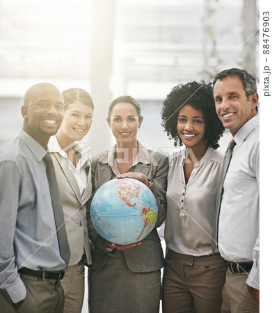 Taking the world by storm. Cropped portrait of a businesswoman holding a globe while standing with her colleagues. Taking the world by storm. Cropped portrait of a businesswoman holding a globe while standing with her colleagues. 88476903