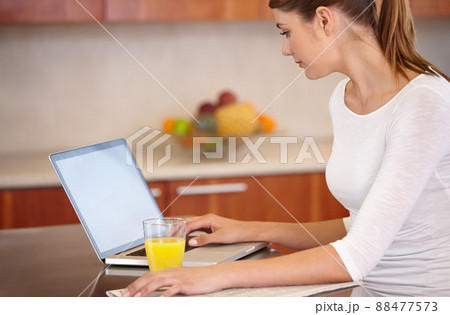 Catching up on current events. Cropped shot of an attractive young woman using her laptop while relaxing at home. 88477573