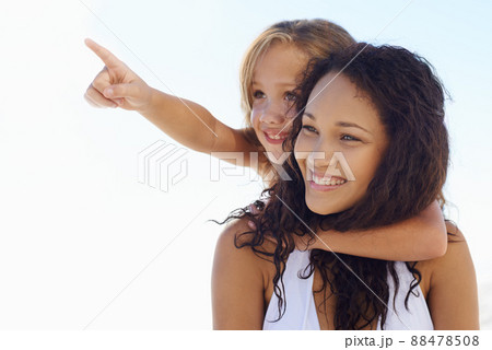 Look at the seagulls. A young mother piggybacking her little girl while shes pointing at something in the distance. 88478508