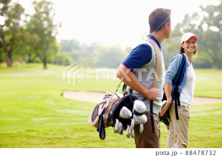 Female golfer smiling and looking at man. Focus on female golfer smiling and looking at man. Female golfer smiling and looking at man. Focus on female golfer smiling and looking at man. 88478732