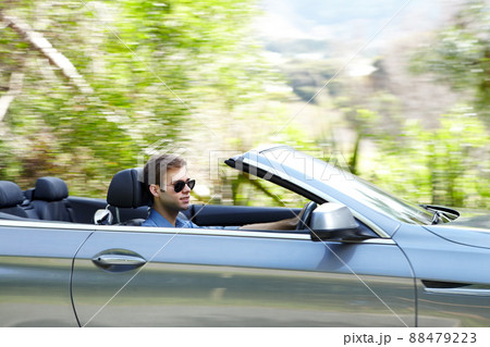 He loves his convertible. A young male driving a silver convertable. He loves his convertible. A young male driving a silver convertable. 88479223