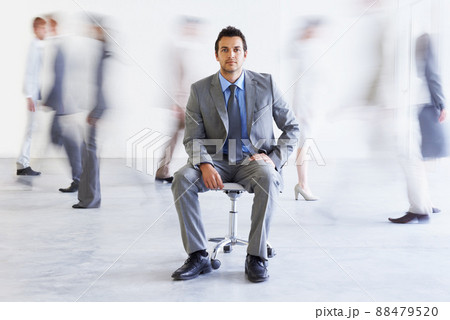 Keeping calm during the rush. Conceptual portrait of a young executive sitting as colleagues stream passed him hastily. 88479520