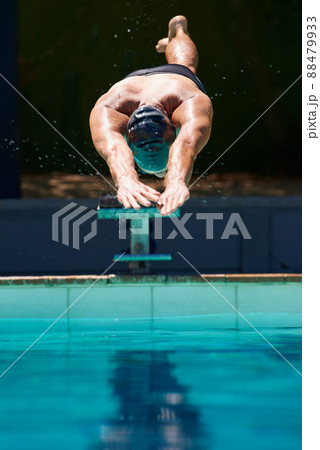Starting the race. A young man diving off a starting block. 88479933