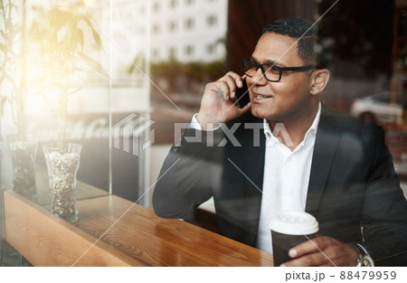 I just got here.... High angle shot of a handsome mature businessman making a phonecall message while sitting in a coffee shop. 88479959