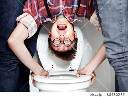 Hes an easy target. Closeup portrait of a nerdy guy getting dunked in the school toilet. 88480286