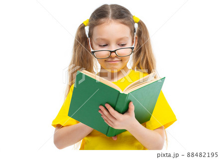 Cheerful young child girl with glasses holding a book to study isolated on a white background. Cheerful young child girl with glasses holding a book to study isolated on a white background. 88482195