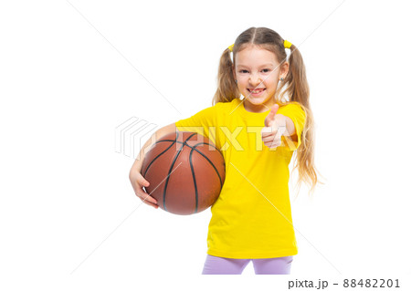 Little cute girl holding a basketball in her hand and showing a like gesture. Isolated on white background. 88482201