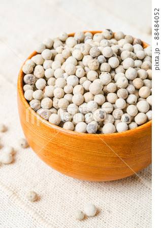 White pepper seeds (peppercorn) in wooden bowl on tablecloth background. 88484052
