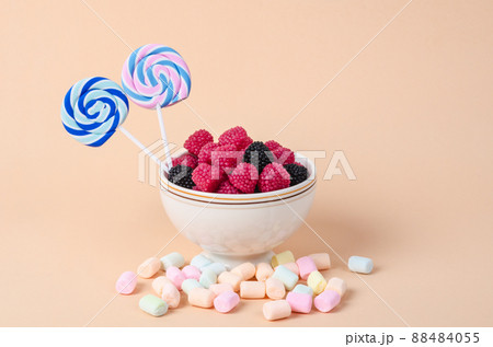 Sweet gummy in cup and marshmallow on pastel orange background. 88484055