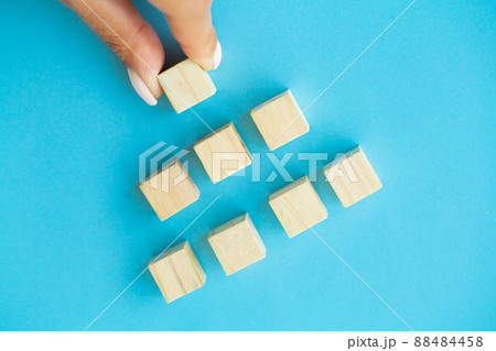 Business concept, hand places wooden cubes on blue background Business concept, hand places wooden cubes on blue background 88484458