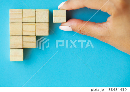 Business concept, hand places wooden cubes on blue background Business concept, hand places wooden cubes on blue background 88484459