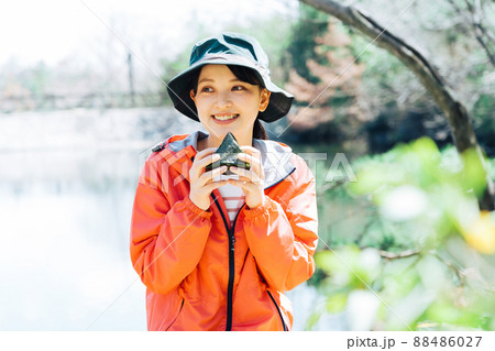 自然の中でおにぎりを食べる女性 88486027
