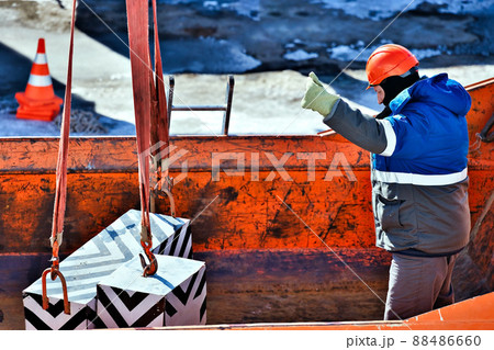 Working slinger loads blocks or loads into back of truck. Slinger operates outside on winter day 88486660