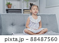 A girl is meditating inside the house. 88487560