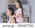 The daughter is giving a massage to her mother. 88487562