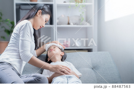 A girl is sick with a fever and her mother is taking care of her. A girl is sick with a fever and her mother is taking care of her. 88487563