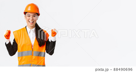 Successful winning female asian engineer, construction architect in protective glasses, gloves and helmet triumphing, fist pump rejoice and say yes, achieve goal, white background Successful winning female asian engineer, construction architect in protective glasses, gloves and helmet triumphing, fist pump rejoice and say yes, achieve goal, white background 88490696