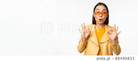 Enthusiastic asian girl in sunglasses, shows okay, ok sign in approval, smiling and laughing, approve, recommend smth, praise and compliment, standing over white background Enthusiastic asian girl in sunglasses, shows okay, ok sign in approval, smiling and laughing, approve, recommend smth, praise and compliment, standing over white background 88490835