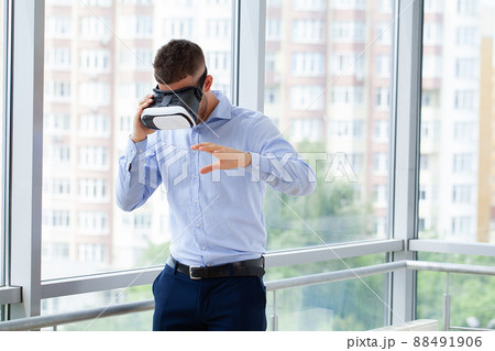Shot of a young businessman wearing a VR headset in an office Shot of a young businessman wearing a VR headset in an office 88491906