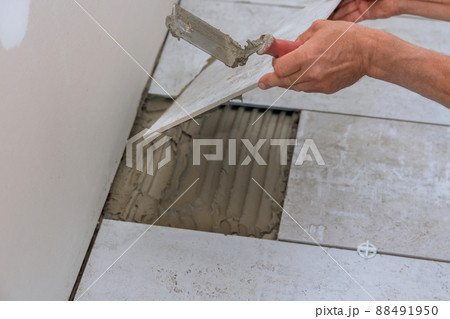 Man installs placing the ceramic tile over floor 88491950