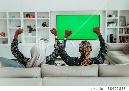 African Couple Sitting On Sofa Watching TV Together Chroma Green Screen Woman Wearing Islamic Hijab Clothes African Couple Sitting On Sofa Watching TV Together Chroma Green Screen Woman Wearing Islamic Hijab Clothes 88492853