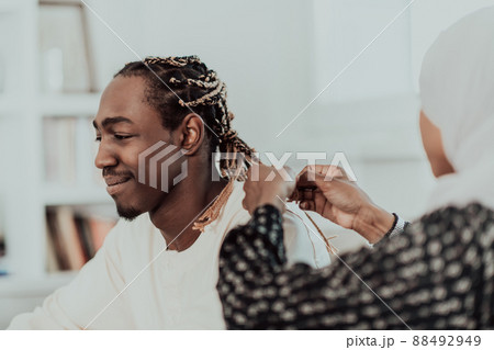 A young Muslim couple has a romantic time at home while the woman makes the hairstyle for her husband female wearing traditional Sudan Islamic hijab clothes. 88492949