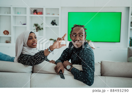 African Couple Sitting On Sofa Watching TV Together Chroma Green Screen Woman Wearing Islamic Hijab Clothes African Couple Sitting On Sofa Watching TV Together Chroma Green Screen Woman Wearing Islamic Hijab Clothes 88493290