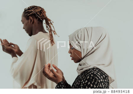 Handsome Young African Muslim Man And Muslim Hijab Woman Making Traditional Fatiha Prayer To Allah God While Wearing A Traditional Sudan fashion clothes in studio Handsome Young African Muslim Man And Muslim Hijab Woman Making Traditional Fatiha Prayer To Allah God While Wearing A Traditional Sudan fashion clothes in studio 88493418