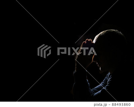 Young man praying on dark background Young man praying on dark background 88493860