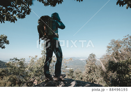 Successful hiker taking photo on sunrise mountain top cliff edge Successful hiker taking photo on sunrise mountain top cliff edge 88496193