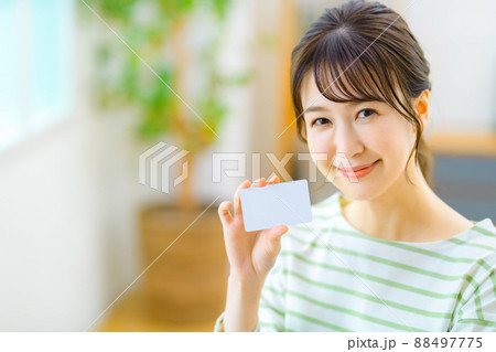 リビングでネットショッピングするカードを持ったカメラ目線の若い主婦 リビングでネットショッピングするカードを持ったカメラ目線の若い主婦 88497775