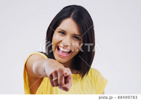 Its your turn to shine. Portrait of a beautiful young woman pointing to the camera against a grey background. 88499783