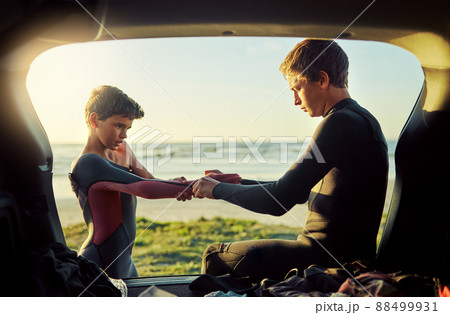 Thats what big brothers are for. Shot of a young surfer helping his little brother put on his wetsuit at the beach. Thats what big brothers are for. Shot of a young surfer helping his little brother put on his wetsuit at the beach. 88499931