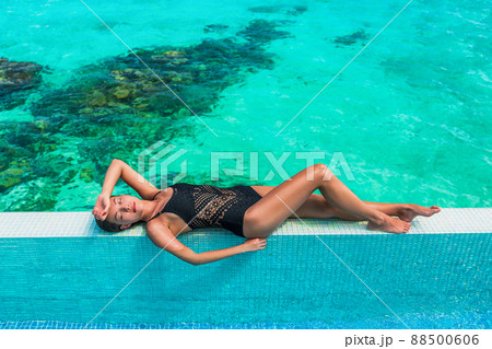 Luxury suntan beauty Asian swimsuit model woman lying down sunbathing on idyllic infinity swimming pool travel bikini girl vacation sun tan over turquoise ocean in Bora Bora Tahiti, French Polynesia 88500606