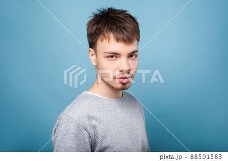Portrait of concentrated confident brunette man with small beard and mustache in casual sweater looking attentively with intelligent serious expression. indoor studio shot isolated on blue background 88501583