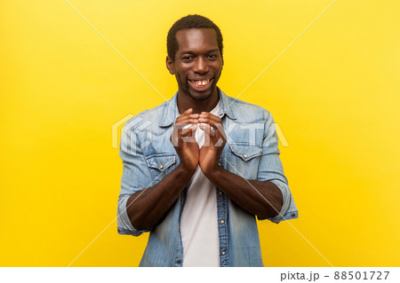 Portrait of sneaky devious man in denim casual shirt with rolled up sleeves smiling, twiddling fingers and thinking cunning idea, planning evil trick. indoor studio shot isolated on yellow background 88501727