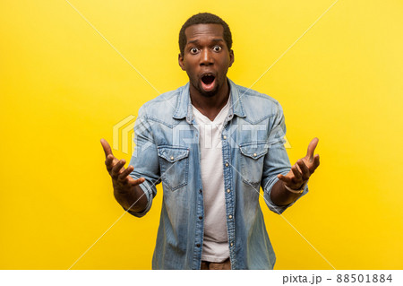 What do you want from me. Portrait of irritated angry man in denim shirt raising hands while disputing in conflict, looking annoyed and indignant. indoor studio shot isolated on yellow background 88501884