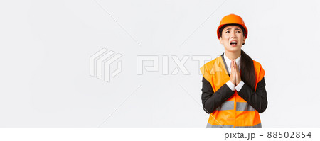 Desperate and reckless asian female construction manager, architect pleading god, wearing safety helmet, holding hands in pray, supplicating, asking god help, begging over white background Desperate and reckless asian female construction manager, architect pleading god, wearing safety helmet, holding hands in pray, supplicating, asking god help, begging over white background 88502854