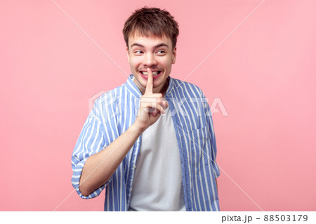 Funny secret, don't tell anyone. Portrait of positive brown-haired man with small beard and mustache in shirt showing silence gesture, looking aside. indoor studio shot isolated on pink background 88503179
