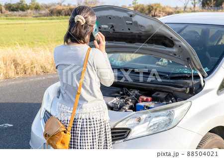 エンジントラブルで途方に暮れる女性　電話をかける 88504021