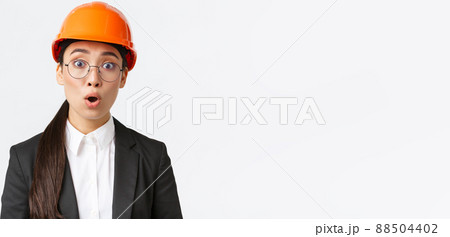 Close-up of shocked and concerned asian female engineer hear bad news, worrying announcement, standing in safety mask, glasses and business suit and gasping startled, white background Close-up of shocked and concerned asian female engineer hear bad news, worrying announcement, standing in safety mask, glasses and business suit and gasping startled, white background 88504402