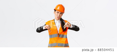 Disappointed and upset asian female chief engineer inspect bad work, showing thumbs-down disappointed, wear safety helmet and complaining weak awful work of architect, white background Disappointed and upset asian female chief engineer inspect bad work, showing thumbs-down disappointed, wear safety helmet and complaining weak awful work of architect, white background 88504451